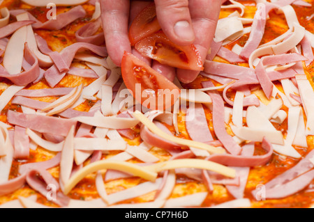 Le chef met sur la pizza aux tomates Banque D'Images