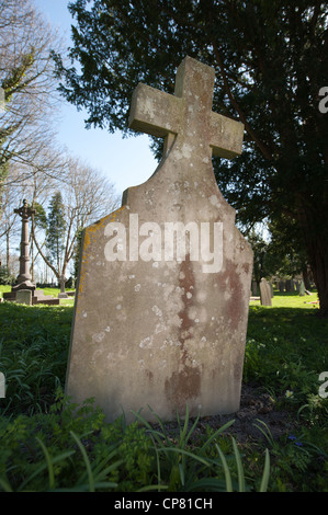Pierre tombale avec une croix dans le cimetière de l'Église d'Angleterre se distingue en arrière-plan Banque D'Images