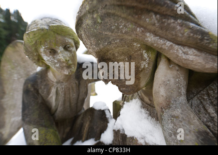 Statue angel sympathique très froid me fixe avec un compagnon et de gouttes froides le nez dans la neige cimetière lié Banque D'Images