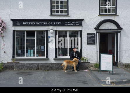 L'homme et le chien assis à l'extérieur de la galerie de Beatrix Potter, dans le village de Hawkshead, Parc National de Lake District, Cumbria, Royaume-Uni Banque D'Images