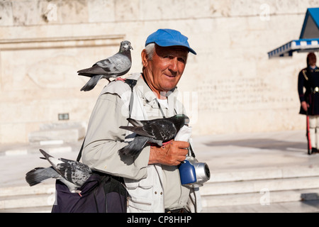 Les gens d'attirer les pigeons sur leurs bras tendus et la tête. Le Parlement grec, place Syntagma. Athènes, Attique, Grèce. Banque D'Images