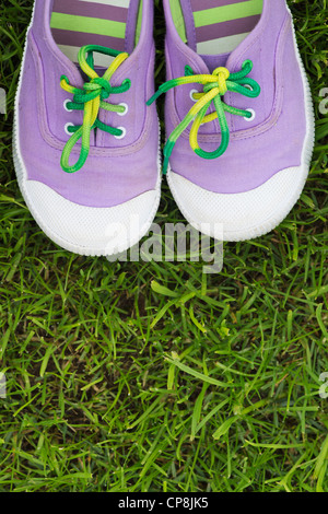 Plimsolls childs colorés sur une pelouse Banque D'Images