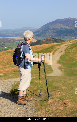 Senior woman à l'aide de bâtons de marche pour la marche sur un chemin jusqu'Catbells dans Parc National de Lake District. Keswick Cumbira England UK Banque D'Images