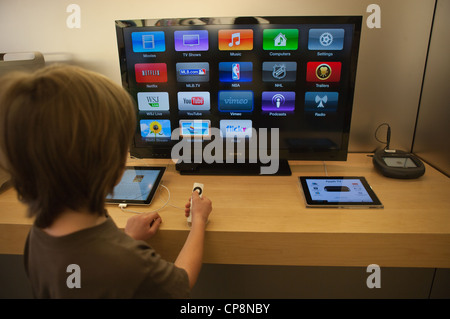 Enfant de faire défiler les choix sur Apple TV, grand écran. Banque D'Images