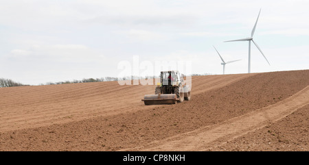 Travail du tracteur un champ labouré avec les éoliennes dans l'arrière-plan, Fullabrook Wind Farm, North Devon, UK Banque D'Images