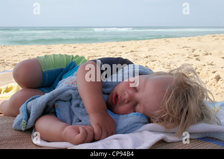 Petit garçon prend une sieste sur la plage pendant les vacances d'été Banque D'Images