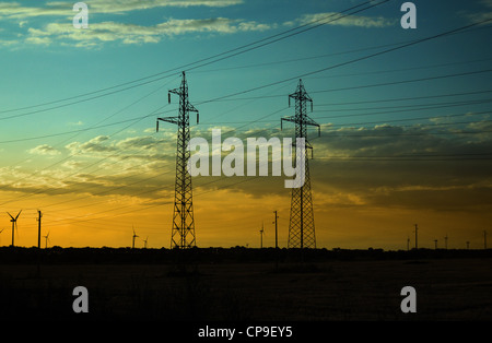 Silhouettes de piliers et d'électricité éoliennes sur le coucher du soleil Banque D'Images