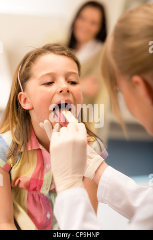 Petite fille ayant l'examen de la gorge avec abaisse-langue Banque D'Images