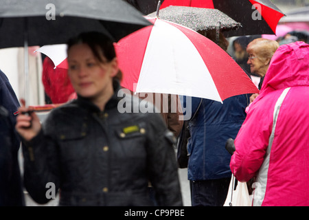 Gens portant des parapluies en ville à pied sous la pluie d'Irlande Royaume-Uni Banque D'Images