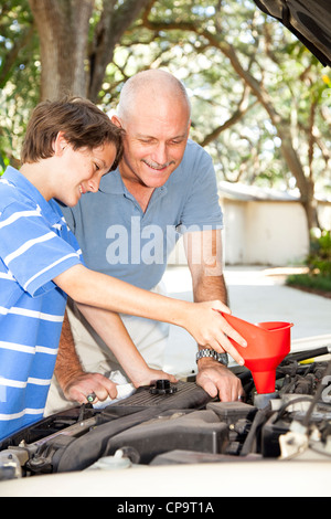 Père et fils le changement d'huile sur la voiture familiale. Banque D'Images
