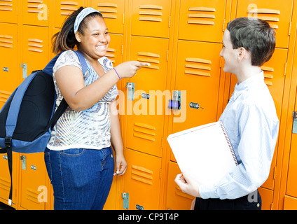 Middle school boy and girl rire et plaisanter ensemble par leurs casiers. Banque D'Images