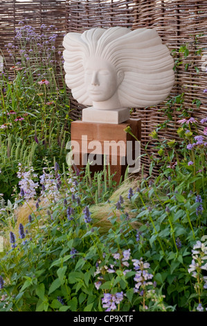 Tête de la sculpture sur pierre est une fonctionnalité sur bordure de fleurs aux couleurs vives - "rêves que des rêves' show garden, RHS Flower Show, Tatton Park, Angleterre, RU Banque D'Images