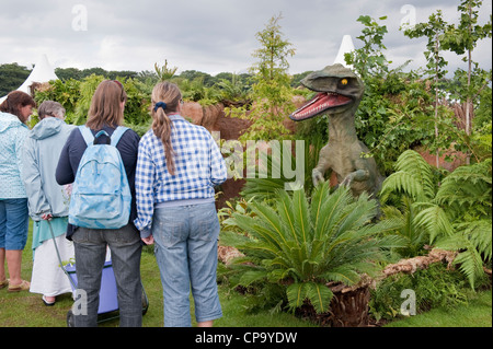Personnes voir raptor féroce, Vert Fougères et palmiers dans le jardin spectacle primé (Dinosaures à grande pièce) - RHS Flower Show, Tatton Park, Cheshire, Royaume-Uni. Banque D'Images