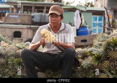 Coupe homme un ananas dans le marché flottant de Cai Rang, près de Can Tho, Delta du Mekong, Vietnam Banque D'Images