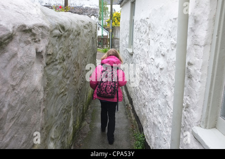 Une fillette de 9 ans se rend à l'école sous la pluie à Flushing, Cornwall, UK Banque D'Images