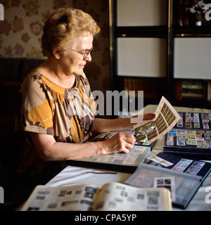 Femme âgée avec une collection de timbres-poste Banque D'Images