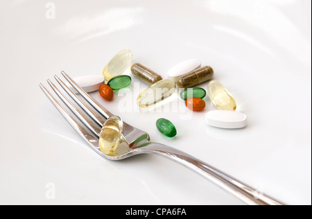 Sélection de vitamines (omega 3, Co-enzyme Q10, menthe, chondroïtine, ginkgo et ginseng) avec la fourchette sur fond blanc. Banque D'Images