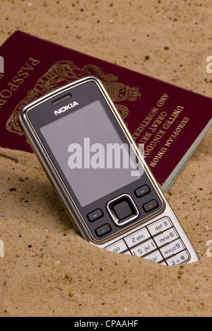 Passeport perdu et pose de téléphone mobile dans le sable. Banque D'Images