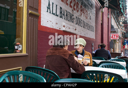 Un couple de touristes prendre un café tout en lisant un guide sur Mulberry Street dans la Petite Italie, la ville de New York. Banque D'Images