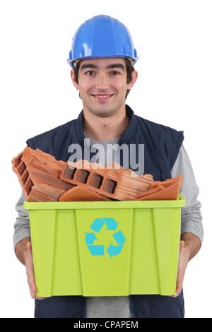 Jeune charpentier transportant le recyclage à remous plein de briques rouges Banque D'Images