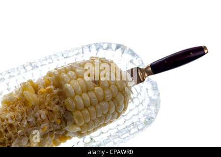 À moitié mangé le maïs cuit dans un plat en verre husk isolés contre white Banque D'Images