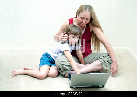 Grand-mère et petite-fille de passer du temps ensemble avec un ordinateur tout en étant assis sur le plancher Banque D'Images