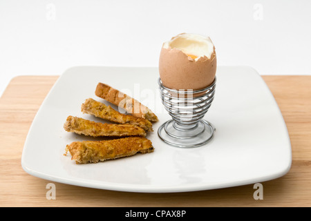 Soldats et toast en metal egg cup sur fond blanc Banque D'Images