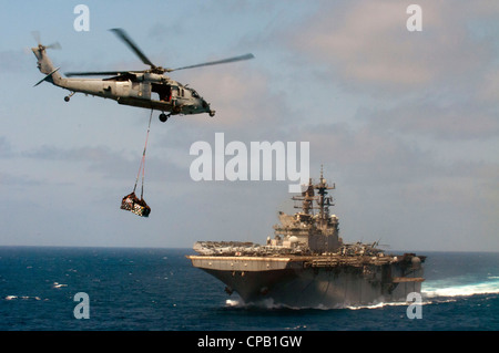 Un hélicoptère MH-60S Sea Hawk livre du fret au navire d'assaut amphibie USS Makin Island (LHD 8) lors d'un réapprovisionnement en mer avec l'huileur de la flotte du Commandement militaire de Sealift USNS Patuxent (T-AO 201). Le groupe de préparation amphibie de l'île Makin est déployé pour soutenir les opérations de sécurité maritime et les efforts de coopération en matière de sécurité du théâtre dans le domaine de responsabilité de la 5e flotte américaine. Banque D'Images