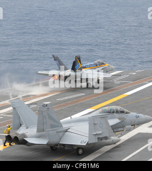 Un Hornet F/A-18C affecté aux Blue Diamonds of Strike Fighter Squadron (VFA) 146 à partir du porte-avions USS Nimitz (CVN 68) En tant que Super Hornet F/A-18F affecté au Black Knights of Strike Fighter Squadron (VFA) 154 taxis pour catapulter un en préparation au lancement à partir du pont de vol. Nimitz est en train de conduire des qualifications de transporteur au large de la côte sud de la Californie. Banque D'Images