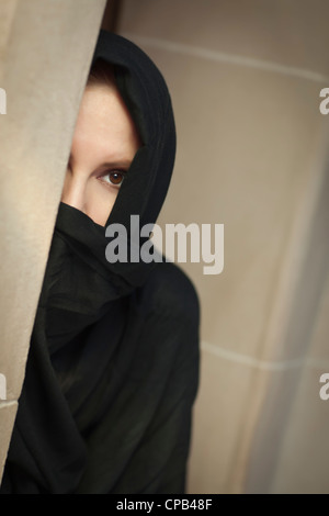Femme islamique prudente dans une sous-fenêtre portant le niqab ou Burqa traditionnelle. Banque D'Images