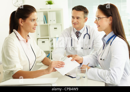 Portrait de femme en donnant l'enveloppe avec de dollars à l'hôpital de thérapeute Banque D'Images