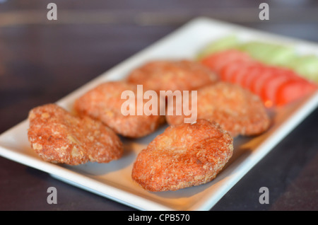 Gâteau de poisson frit épicé (Tod Mun Pla) servi avec tomate et concombre Banque D'Images