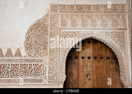 Reliefs ornementaux autour d'une porte en bois voûté dans les Palais Nasrides de l'Alhambra à Grenade, Espagne. Banque D'Images