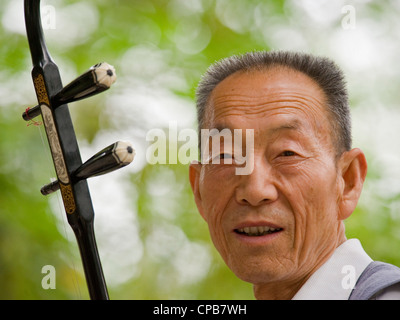 Un musicien chinois jouant l'instrument traditionnel chinois, l'erhu, Le violon chinois - tôt le matin, à un parc de Jiuquan. Banque D'Images