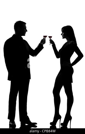 Un couple homme et femme buvant du vin rouge toasting in silhouette studio isolé sur fond blanc Banque D'Images