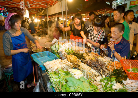 Une femme chinoise la vente de snack food célèbre Zhengning nuit Route de la rue du marché alimentaire à Lanzhou. Banque D'Images