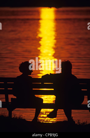 Coucher du soleil à Greenlake avec la silhouette du couple sur banc de parc assis et la conversation tout en appréciant le magnifique coucher de Seattle Banque D'Images