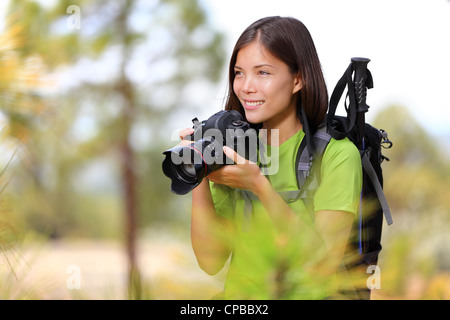 Belle jeune métisse asiatique chinois / Caucasian female hiker photographing par appareil photo reflex professionnel dans l'aménagement forestier Banque D'Images