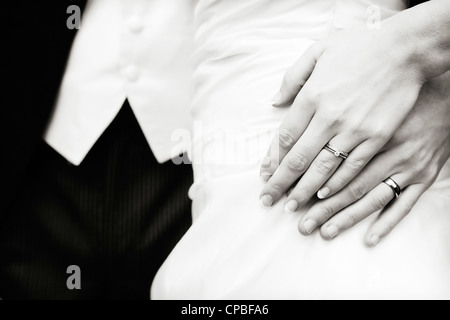 Mariée et marié affichant leurs anneaux de mariage, avec leurs mains se chevauchant Banque D'Images