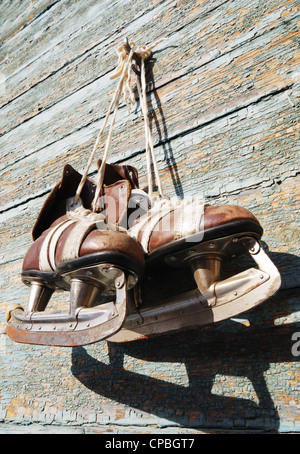 Vintage paire de patins à glace mens accrochée à un mur en bois Banque D'Images