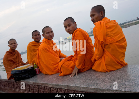 Portrait horizontal de cinq moines bouddhistes cambodgiens assis sur les rives de la rivière Tonle Sap pour regarder le soleil se coucher. Banque D'Images