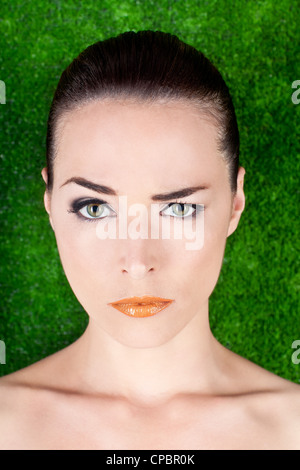 Closeup portrait of a de graves belle femme haussant un sourcil sur fond vert Banque D'Images