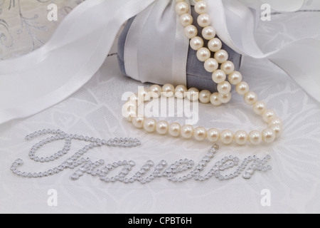 Image féminine avec Word, 'traveler' en faux diamants mis sur damassé blanc et entouré de perles, boîte cadeau en velours. Banque D'Images