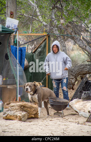 Une femme sans-abri et ses chiens vivent dans une cabane de toile à l'extérieur en campement dans la ville désertique de Victorville, CA. Banque D'Images