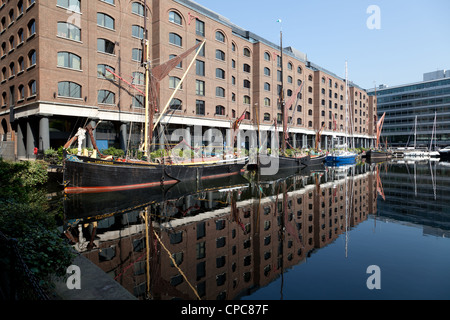 Vieux bateau à barges et les bâtiments reflètent dans l'eau de St Katharine Docks marina, East London Banque D'Images