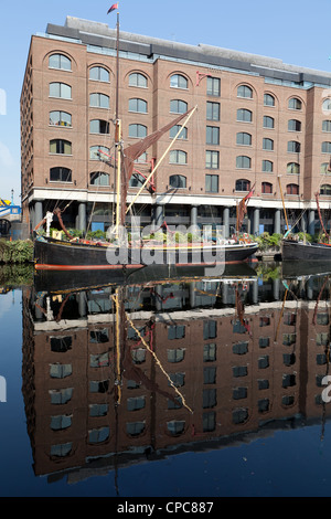 Vieux bateau à barges et les bâtiments reflètent dans l'eau de St Katharine Docks marina, East London Banque D'Images