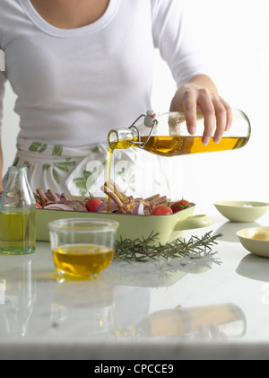 Woman pouring olive oil sur le rôti lave Banque D'Images