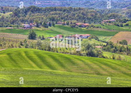 Maisons rurales parmi les vertes collines et les prairies de Piémont au printemps dans le Nord de l'Italie. Banque D'Images