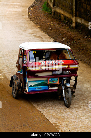 Un tricycle rouge vitesses taxi dans la rue principale de la ville de El Nido sur l'île de Palawan, aux Philippines. Banque D'Images