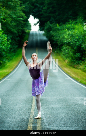 Caucasian ballerina danse sur la route à distance Banque D'Images